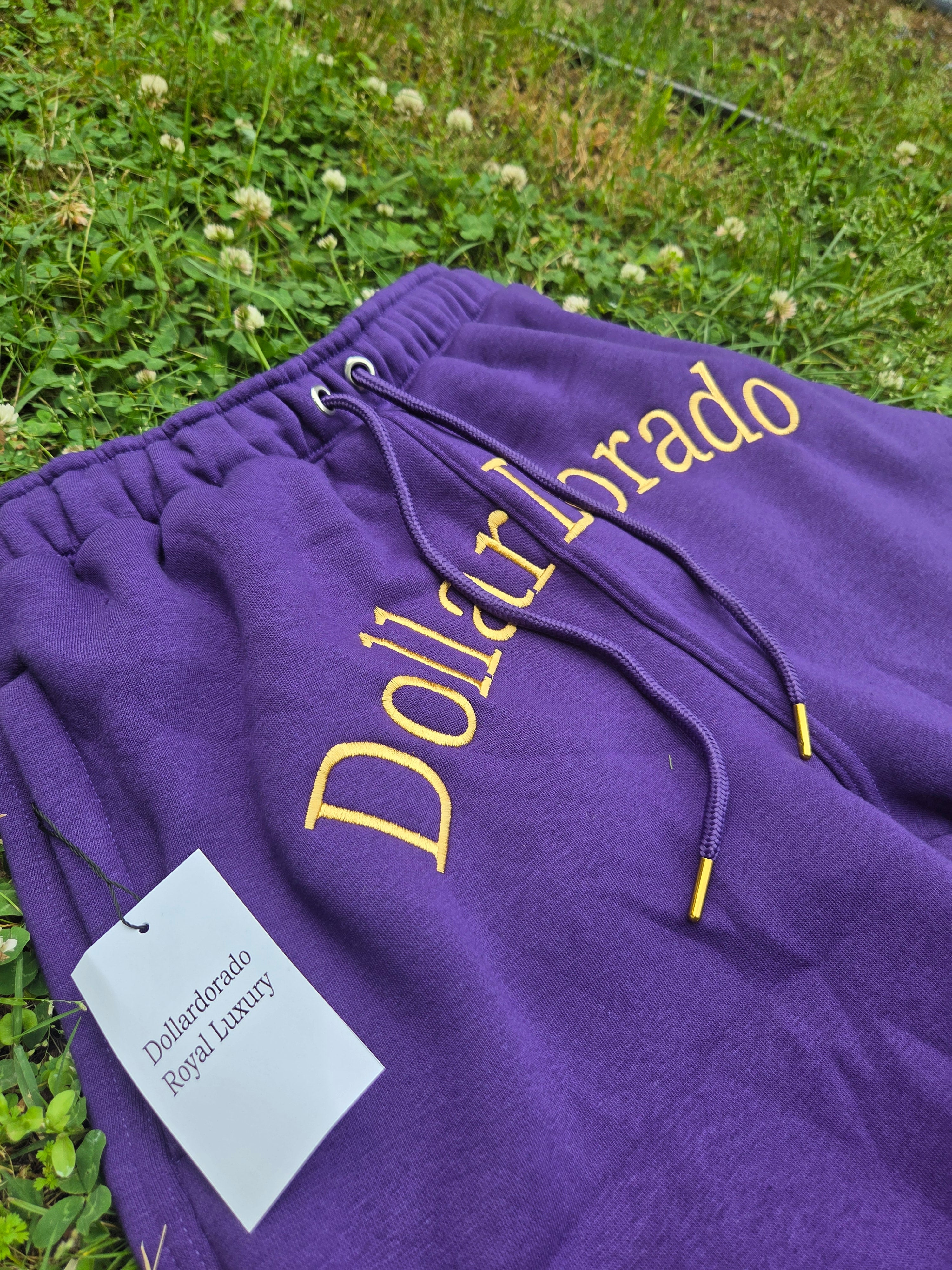"DollarDorado" shorts (thick fleece). Logo and "DD" lettering embroidered in gold thread. Laces with gold metal tips. Navy blue (15 units available). 2 sizes S, 5 sizes M, 8 sizes L. Limited edition. Limited purple sizes: 3 small, 5 medium, 7 large