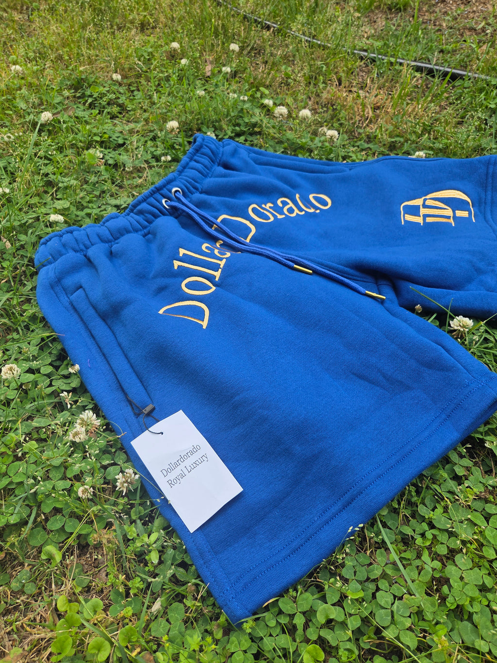 "DollarDorado" shorts (thick fleece). Logo and "DD" lettering embroidered in gold thread. Laces with gold metal tips. Navy blue (15 units available). 2 sizes S, 5 sizes M, 8 sizes L. Limited edition. Limited purple sizes: 3 small, 5 medium, 7 large
