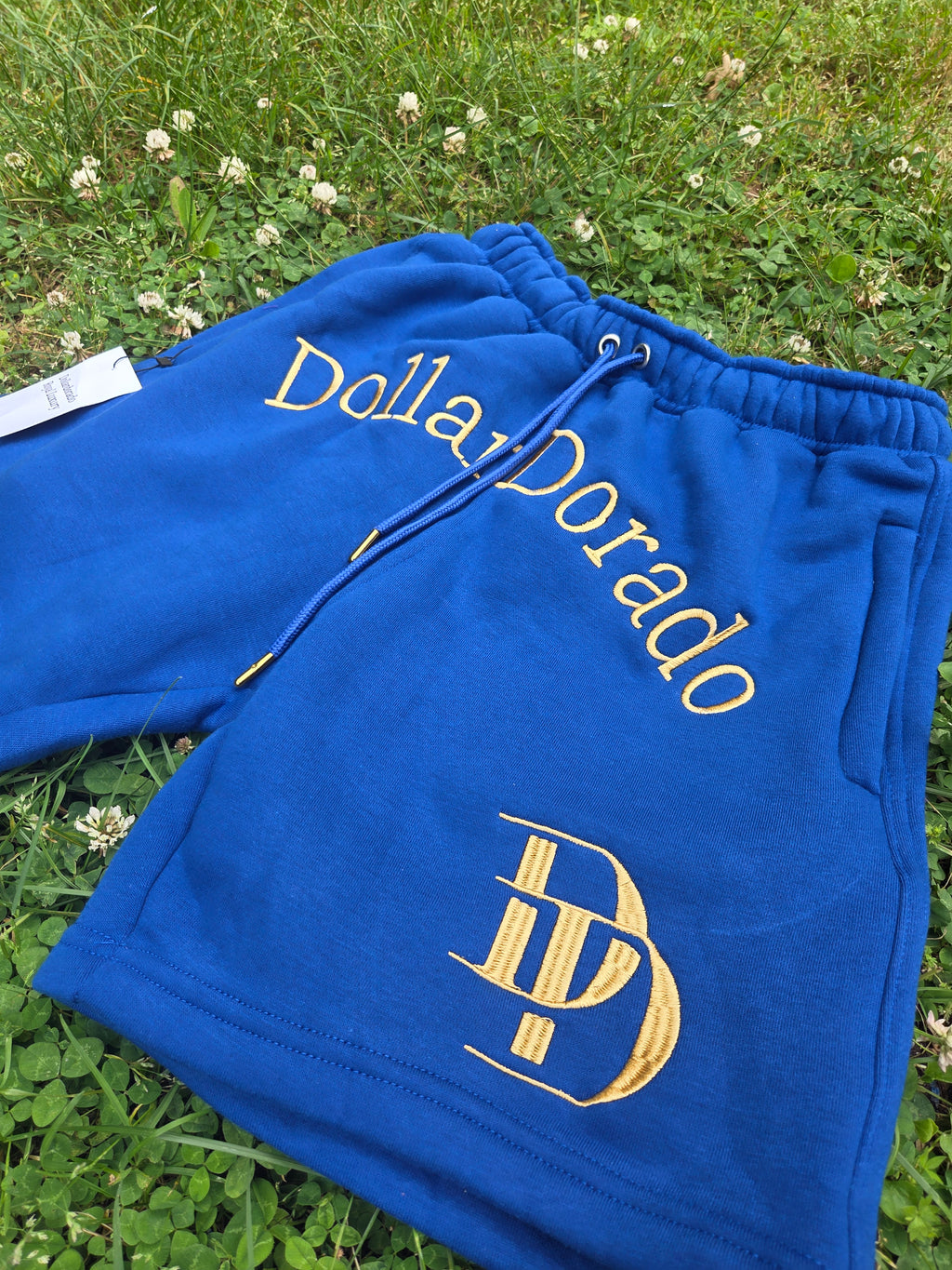 "DollarDorado" shorts (thick fleece). Logo and "DD" lettering embroidered in gold thread. Laces with gold metal tips. Navy blue (15 units available). 2 sizes S, 5 sizes M, 8 sizes L. Limited edition. Limited purple sizes: 3 small, 5 medium, 7 large