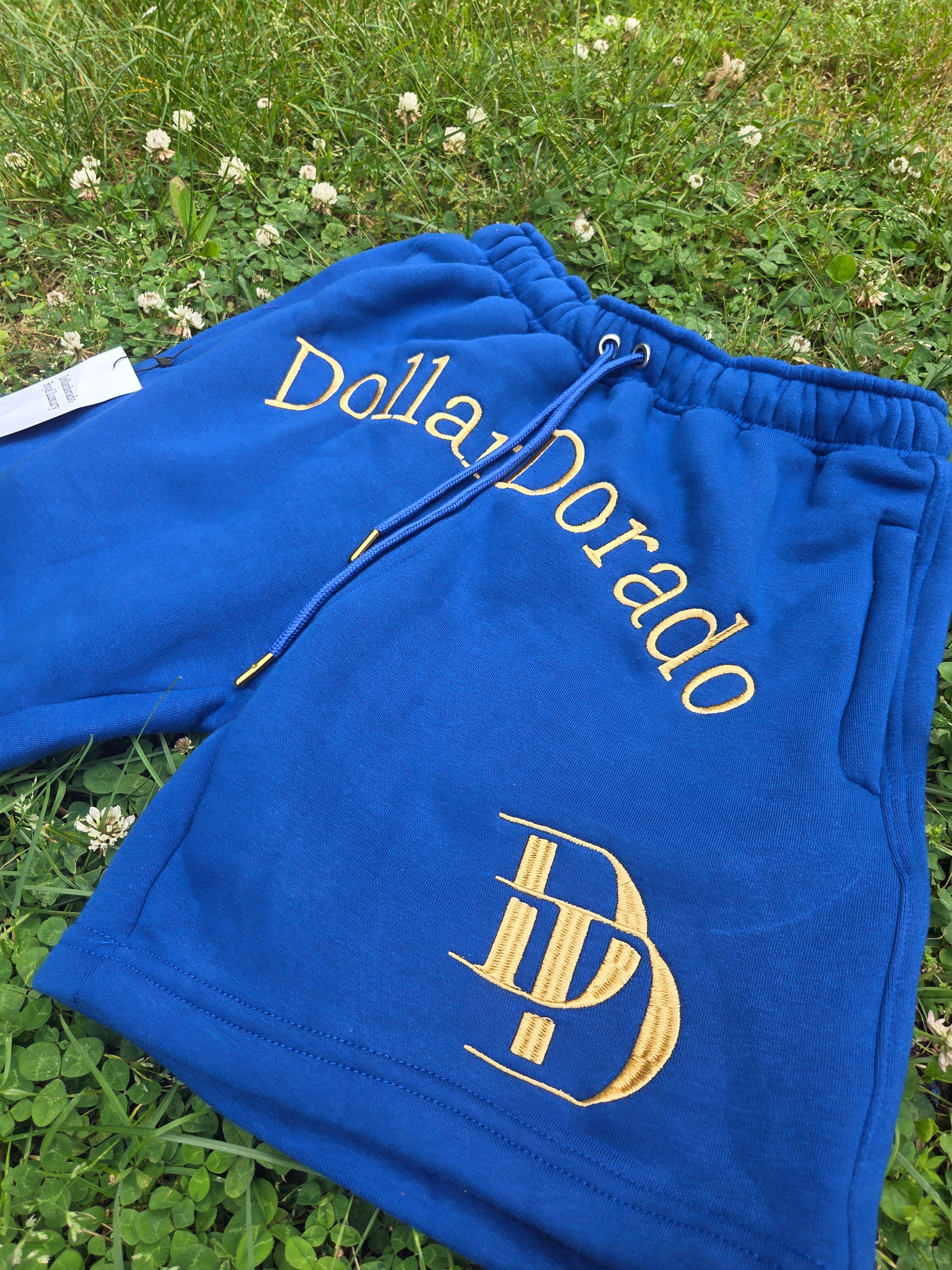 "DollarDorado" shorts (thick fleece). Logo and "DD" lettering embroidered in gold thread. Laces with gold metal tips. Navy blue (15 units available). 2 sizes S, 5 sizes M, 8 sizes L. Limited edition. Limited purple sizes: 3 small, 5 medium, 7 large